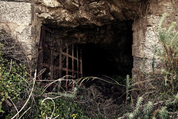 Lost places, Rusty grid barrier in front of a cave in Argientiera