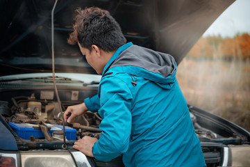 Asian  man having trouble with his broken car