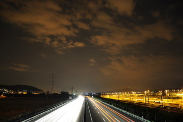 Fototapeta na wymiar Lichtspuren auf Autobahn neben Güterbahnhof