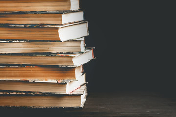 Stack of old books, textbooks on a black background with copy space