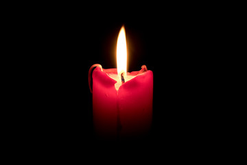 Burning red candle on black background