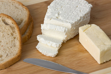 cheese, bread and butter on wooden board