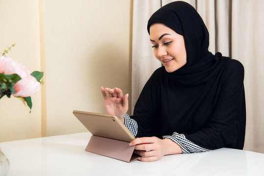 pretty Arabian teen girl using tablet computer in high school classroom