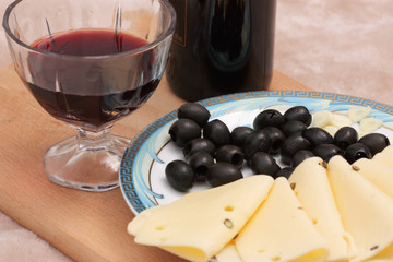 glass of wine, cheese and olive on wooden board
