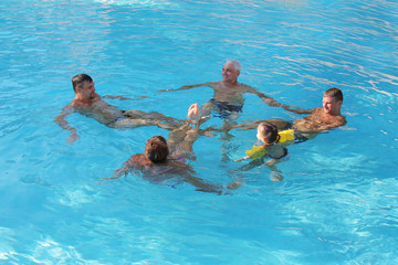 The concept of sports, recreation, healthy lifestyle - 5 people swim in the pool forming a circle....