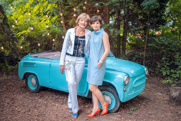 Two women in a vintage car. happy senior mother and adult daughter stand by a retro convertible