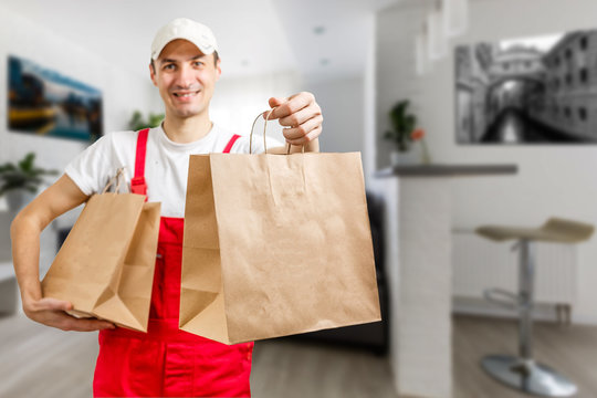 delivery, mail and people concept - happy man delivering food in disposable paper bag to customer home