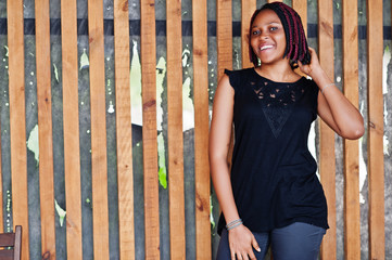 Young african american woman posed against wooden wall.