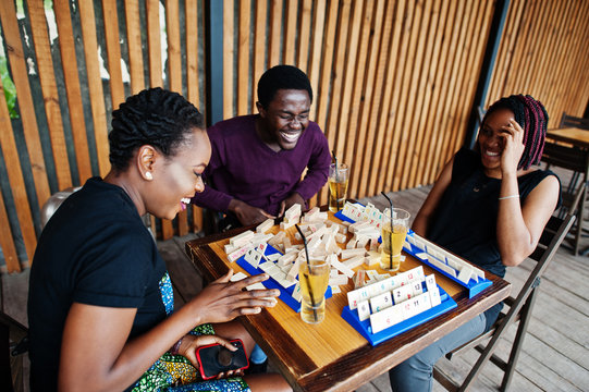 Group of three african american friends play table games.