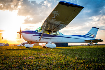 Small private airplanes on the airfield against the backdrop of a colorful sunset