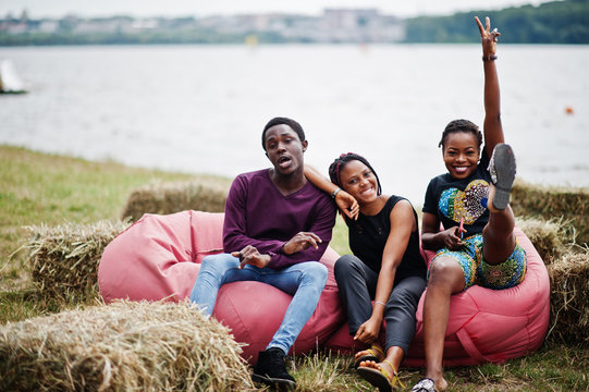 Three African American Friends Chill And Sitting On Poufs Outdoor.