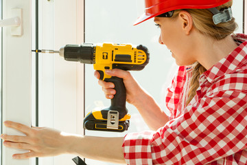 Woman using drill on window