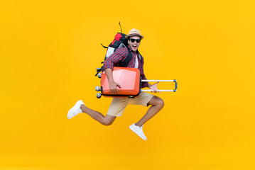 Excited happy young Asian man tourist with luggage jumping