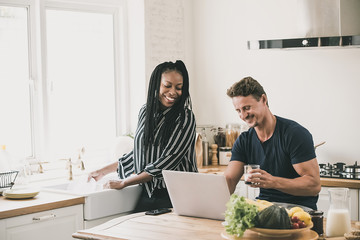 Interracial couple looking at laptop computer together  at home