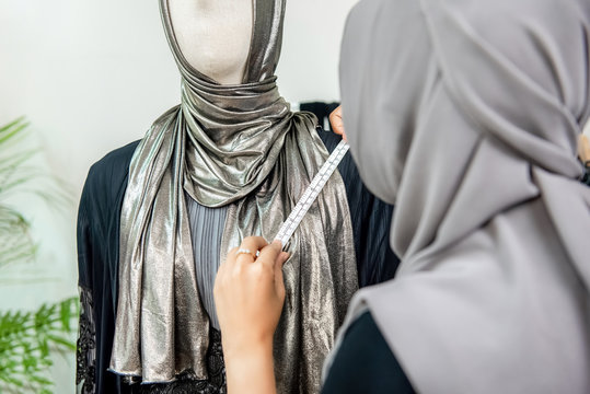 Muslim woman fashion designer measuring size of the dress