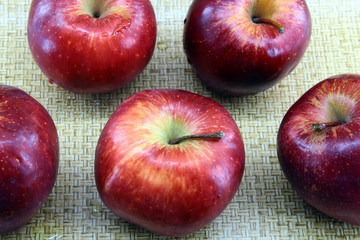 Five red apples on a light brown background