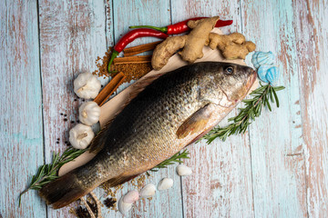 Fresh Golden Snapper on wooden table, Surrounded by spices and raw ingredients