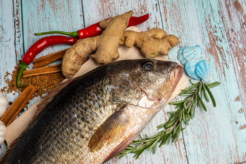Fresh Golden Snapper on wooden table, Surrounded by spices and raw ingredients