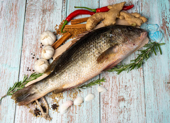Fresh Golden Snapper on wooden table, Surrounded by spices and raw ingredients