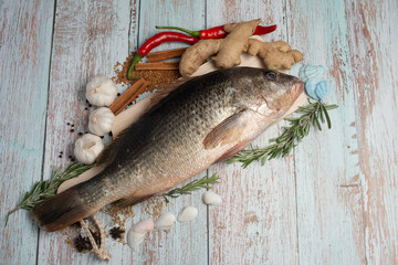 Fresh Golden Snapper on wooden table, Surrounded by spices and raw ingredients