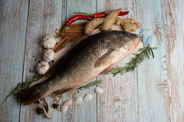 Fresh Golden Snapper on wooden table, Surrounded by spices and raw ingredients