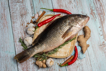 Fresh Golden Snapper on rattan plate, Surrounded by spices and raw ingredients