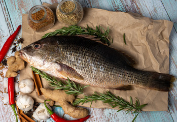 Fresh Golden Snapper on wooden table, Surrounded by spices and raw ingredients