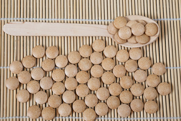 Alternative medicine tablets on a wooden spoon