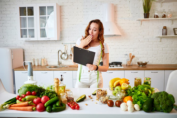 Young beautiful woman using tablet while cooking in the modern kitchen. Healthy eating, vitamins, dieting, technology and people concept. Losing Weight