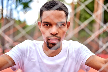 Black basketball player holding the chain link fence with hands