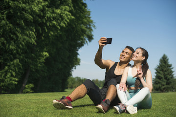 Obraz premium Man and woman taking a selfie in a park