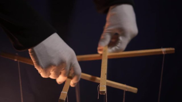 Puppet theatre. Manipulating A Marionette By A Puppeteer. Isolated, black background
