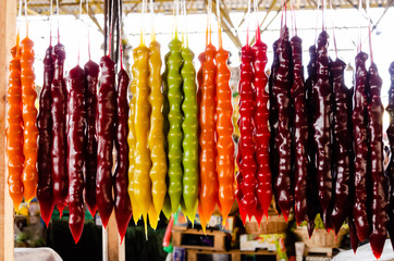 Bright colored churchkhela hanging on the market stall. Traditional Georgian homemade sweets. Closeup