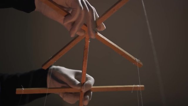 Hands of the puppeteer in white gloves. Marionette control bar with strings