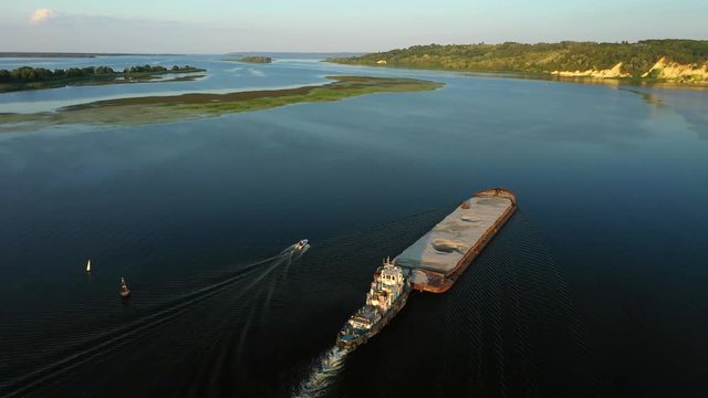 Aerial video river pusher boat transporting barge with dry cargo in middle of summer river, Central Europe