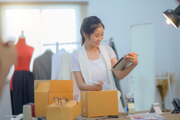 woman tailor made packing goods into boxes containers, ready to delivery to customer under address inform online device
