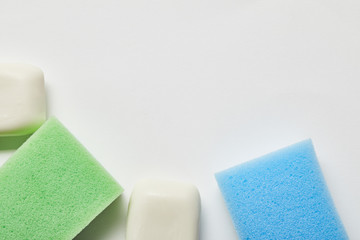 top view of white soaps, green and blue sponges