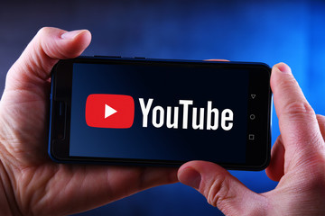 Hands holding smartphone displaying logo of YouTube