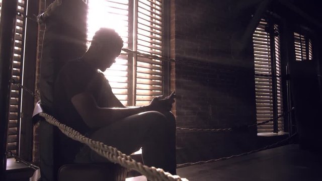 African-american young male boxer sitting in the corner of the ring
