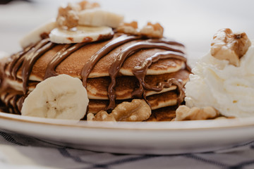 sirope de chocolate sobre pancake casero con nueces y platano