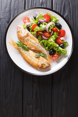 fried pink dorado served with lemon and fresh vegetables close-up on a plate. Vertical top view