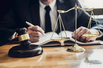 Male lawyer or judge working with contract papers, Law books and wooden gavel on table in...