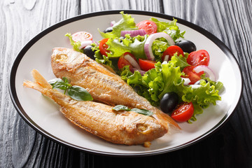 Mediterranean pink dorado served with lemon and fresh vegetables close-up on a plate. horizontal