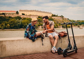 Young couple on vacation having fun driving electric scooter through the city, they looking at map for direction. © Zoran Zeremski