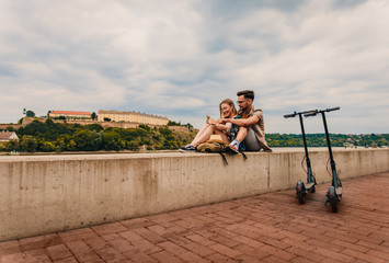 Young couple on vacation having fun driving electric scooter through the city, they looking at map for direction. © Zoran Zeremski