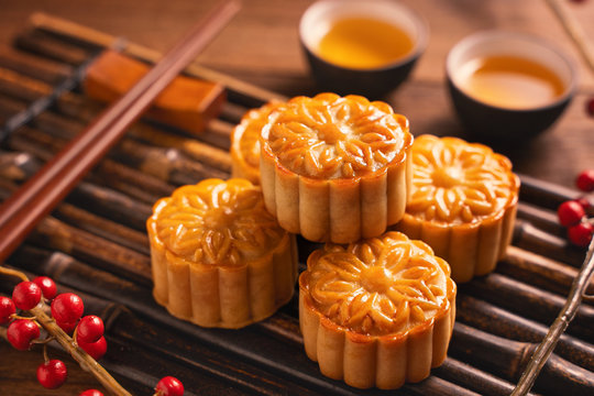 Moon cake Mooncake table setting - Round shaped Chinese traditional pastry with tea cups on wooden background, Mid-Autumn Festival concept, close up.