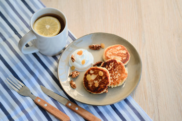 Top view of homemade cheese pancakes syrniki with sour cream and cup of tea