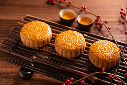 Moon cake Mooncake table setting - Round shaped Chinese traditional pastry with tea cups on wooden background, Mid-Autumn Festival concept, close up.
