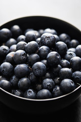 Freshly picked blueberries in black bowl on the table.