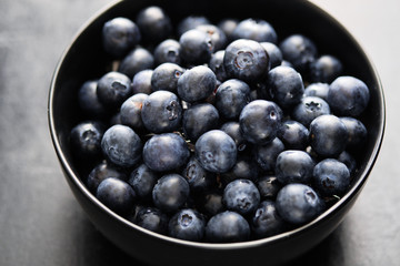 Freshly picked blueberries in black bowl on the table.
